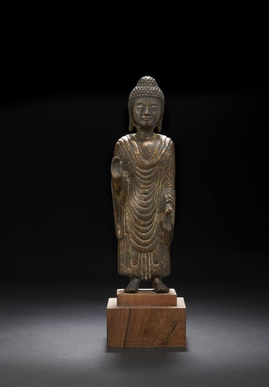 A Korean gilt bronze figure of a standing Buddha, plank-like in form...