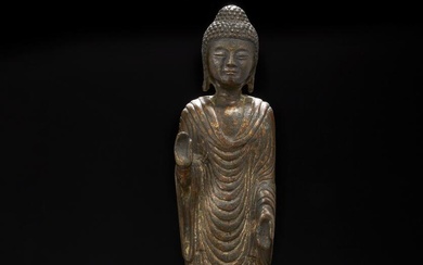 A Korean gilt bronze figure of a standing Buddha, plank-like in form...
