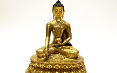 A Tibetan gilt bronze figure of seated Buddha with hand painted temple quality face. H. 30cm