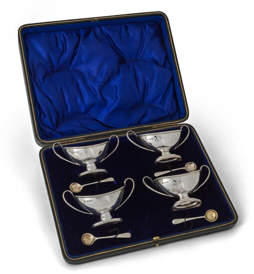 A cased set of four Edwardian silver salts, Sheffield, two 1909 and two 1910, William Hutton & Sons, of oval pedestal form with twin handles and reeded decoration to oval feet, rims and handles, complete with four spoons by the same maker, one...