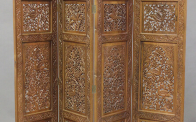 A late 20th century Indian hardwood four-fold dressing screen, profusely carved with panels of birds