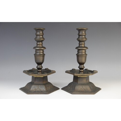 A pair of Arts and Crafts style bronze candlesticks, the hex...