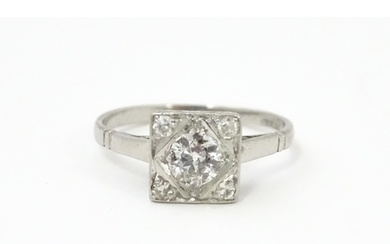 A platinum ring set with central diamond flanked by four dia...