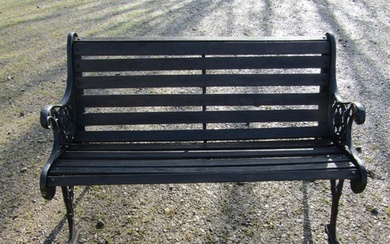 A two seat garden bench with stained wooden slatted seat rai...