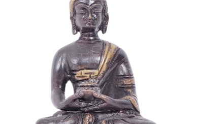 An early 20th century Chinese two tone bronze figurine depicting Buddha. The figure having a blackened ground with gilded crown and details. Modelled in the Lotus position holding pot. Raised on a lotus pedestal base. Measures approx. 11cm tall.