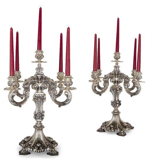 An impressive pair of Portuguese silver five-light candelabra, Porto, 1938-1984, in the 18th century style, the c-scroll branches supporting shaped drip pans and foliate and scroll cast sockets, the baluster stems with shell motifs descending to...