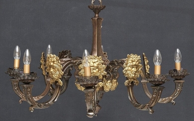 LAMPE 20e siècle Bronze patiné avec masques dorés appliqués, à huit lumières et abat-jour en...