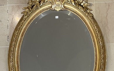 Miroir biseauté Napoléon III de forme ovale en bois et stuc doré surmonté d'un fronton...