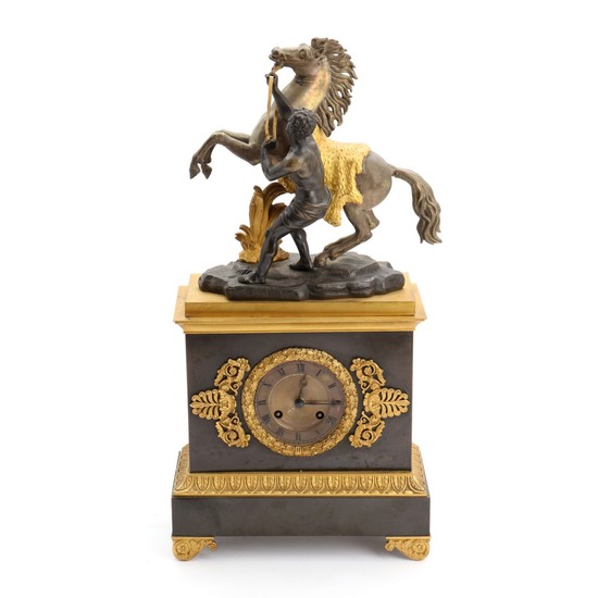 A 19th century Late empire gilded and patinated bronze mantel clock, surmounted by bucking horse and man by G. Coustou. H. 51 cm.