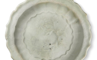 A Chinese porcelain Qingbai foliate dish, Song dynasty, on short foot with curved sides that rise to an everted foliate rim, the interior moulded with floral blooms amidst leafy stems, 11.7cm wide