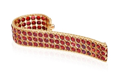 A GARNET AND GOLD BRACELET, CIRCA 1950 The wide band collet...