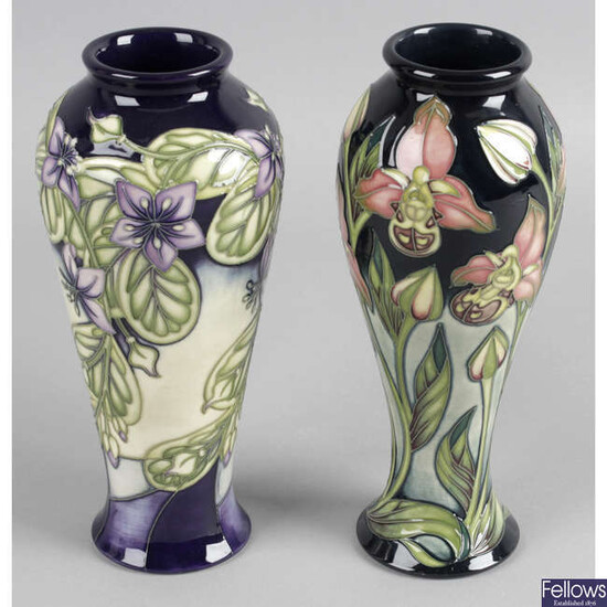 A Moorcroft pottery vase, decorated in a trial pattern of pink flowers, together with another similar example, decorated with lilac flowers. (2).