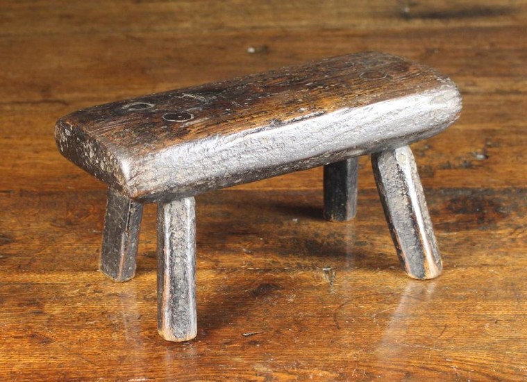 A Small Early 19th Century Rustic Stool. The thick oak plank seat inset with brass headed nails with