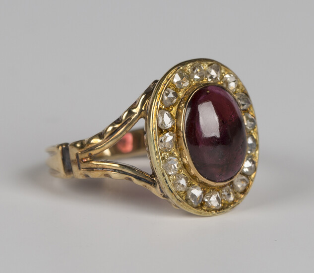 A gold, garnet and diamond oval cluster ring, collet set with an oval cabochon garnet within a surro