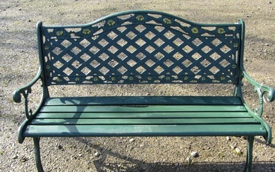 A green painted garden bench with wooden slatted seat beneat...