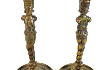 A pair of Aztec style bronze candlesticks raised on...
