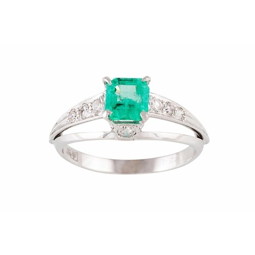 AN EMERALD AND DIAMOND DRESS RING, the trap cut emerald to d...
