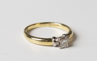 An 18ct gold and diamond single stone ring, claw set with a princess cut diamond between ridged shou