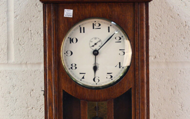 An early 20th century French oak cased electric wall clock, the circular dial with Arabic hours and