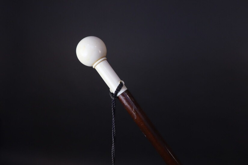 Varnished wood straight shaft cane. Spherical ivory knob. Cracks. Height 88,5 cm