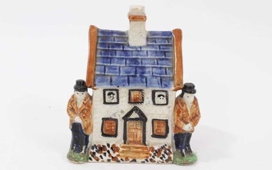 Early 19th century Staffordshire Prattware money box, modelled as a house with figures on either side and faces peering out of the windows