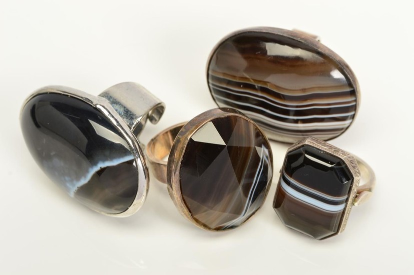FOUR BANDED AGATE RINGS, two designed as oval banded agate c...