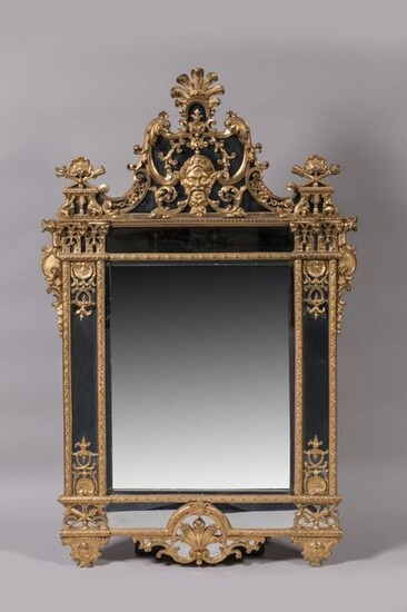 MIRROR with PARECLOSES in carved and gilded wood decorated with plant motifs, interlacing and shells, quivers and trophy flaming torches. In the upper part, a satyr mask with a laurel wreath has its moustache extended in interlacing. The framing...