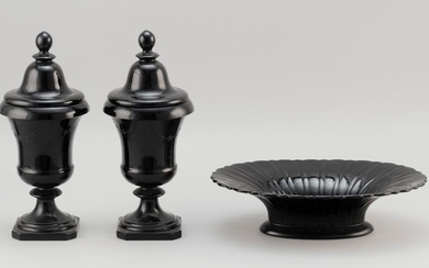 PAIR OF MOLDED BLACK GLASS COVERED URNS AND AN OVAL DISH Urns with knob finials and swag decoration. Heights 11". Widths 6". Dish wi...