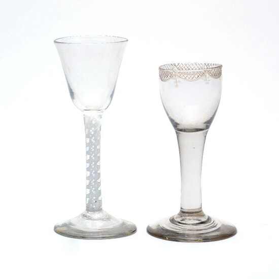 Two wine glasses, early 19th century, comprising an English wine glass, the bell shaped bowl on a barley twist stem, 15cm high, and a Continental wine glass with trellis swag border to the rim on a clear stem, 13cm high (2)