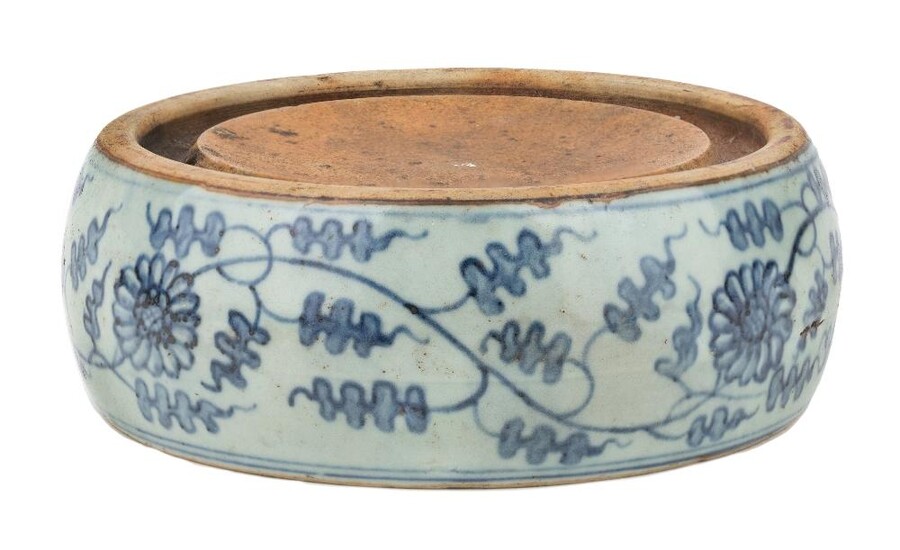 A Chinese blue and white inkstone, 19th century, of compressed barrel form, painted to the sides with leafy chrysanthemums scrolls, apocryphal Wanli six-character mark to base, 16.5cm diameter. Provenance: Estate of the late designer Anthony Powell...