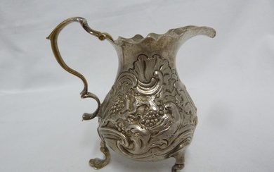A George II silver cream jug, of baluster form embossed with...