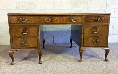 A George III style mahogany veneered kneehole desk, with inset leathered top and seven drawers (