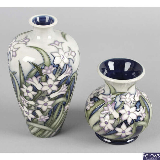 A Moorcroft pottery vase, decorated with a trial pattern of lilac flowers, together with another similar example. (2).