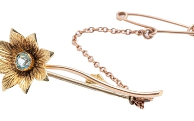 A VINTAGE 15CT GOLD FLOWER BROOCH; daisy set with a synthetic pale blue spinel, length 40mm, with safety chain, wt. 3.10g.