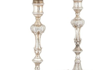 A matched pair of silver candlesticks, one London, 1764, Ebenezer Coker, the other London, 1828, maker TS, both on shaped shell and scroll bases to knopped stems with foliate decoration, bases and removable sconces engraved with crest, 26.5cm high...