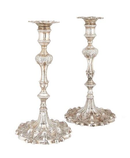 A matched pair of silver candlesticks, one London, 1764, Ebenezer Coker, the other London, 1828, maker TS, both on shaped shell and scroll bases to knopped stems with foliate decoration, bases and removable sconces engraved with crest, 26.5cm high...