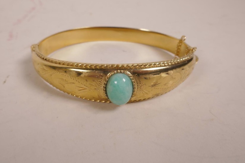 A rolled gold bangle set with a green jade bead, 2½" wide