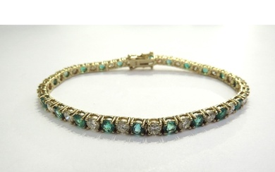 An emerald and diamond line bracelet all in four claw mounts...