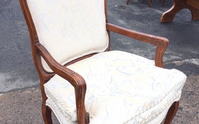 An upholstered armchair with rounded back in moulded frame above...