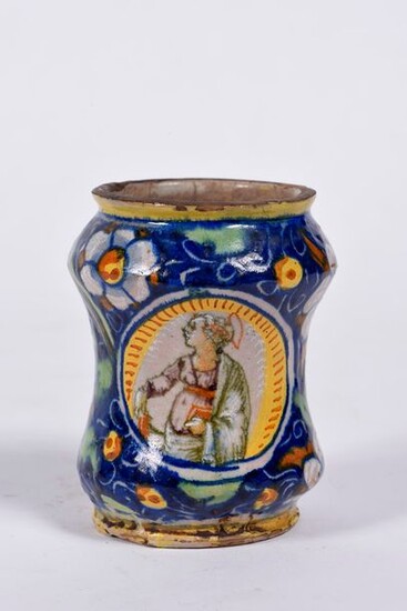Small albarello in majolica decorated with flowers and fruits on a midnight blue background and a portrait of a saint in a medallion. France 16th century. H : 11 cm