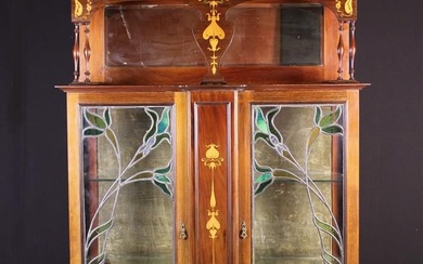 Vitrine en acajou marqueté Art Nouveau. La vitrine est surmontée d'une partie supérieure à dos...