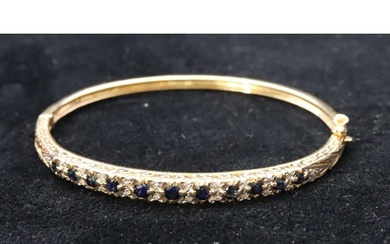 A 9ct gold ladies hinged bangle set with sapphires and diamo...