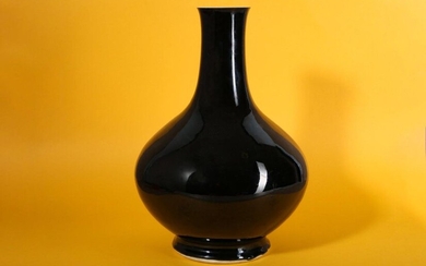 A CHINESE MIRROR BLACK-GLAZED BOTTLE VASE. Qing Dynasty. The compressed ovoid body raised on a splayed foot, rising to a cylindrical neck with a flared rim, a four character underglaze blue Chenghua mark to the base, 34cm H. 清 黑釉撇口瓶，青花「成化年製」楷書款