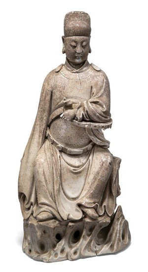 A Chinese Dehua porcelain white glazed figure of Wen Chang, 17th century, the God of Literature finely modelled seated on a pierced rockwork plinth, wearing flowing robes incised with a dragon rank badge, his features finely detailed for insertion...