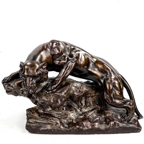 A bronze patinated plaster sculpture, lioness on a rock, mid...