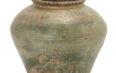 A large Chinese green glaze stone ware jar, Han dynasty, of tapered form rising broad shoulders with ribbed decoration and a lipped rim, covered over all with green glaze that is partially degraded to a silvery iridescence, 28cm high Provenance:...