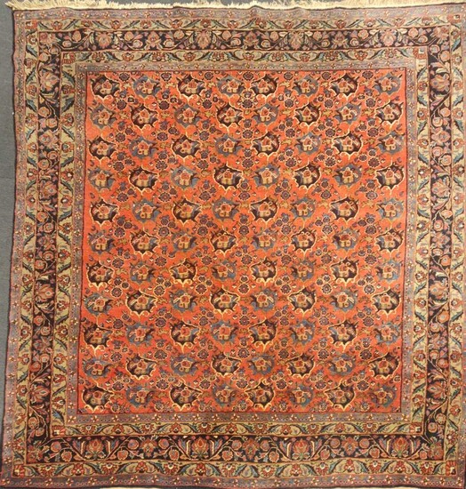 A large red ground rug with repeating floral motif and floral border, 375 x 302cmTassles to one