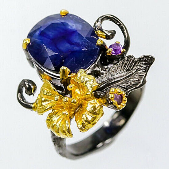 A sapphire and amethyst ring set with an oval-cut sapphire and smaller circular-cut amethysts, mounted in black rhodium and gold plated sterling silver.