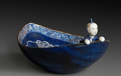 COUPE DE FORME OVALE évoquant une barque, en porcelaine émaillée bleu, ornée à l'intérieur d'une fleur stylisée en bleu et blan...