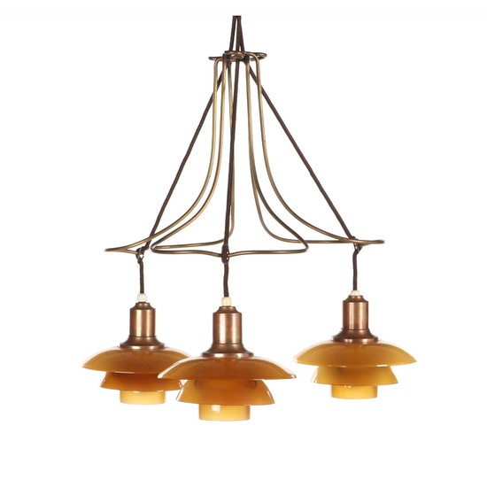 Poul Henningsen: “PH-2/2 Butterfly”. Chandelier with brass frame and copper sockethouses, three lights with amber colored glass. Diam. 52 cm.